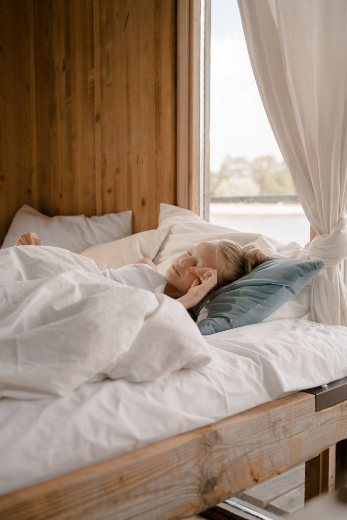 About A young girl waking up in a cozy wooden bedroom with natural light streaming in.