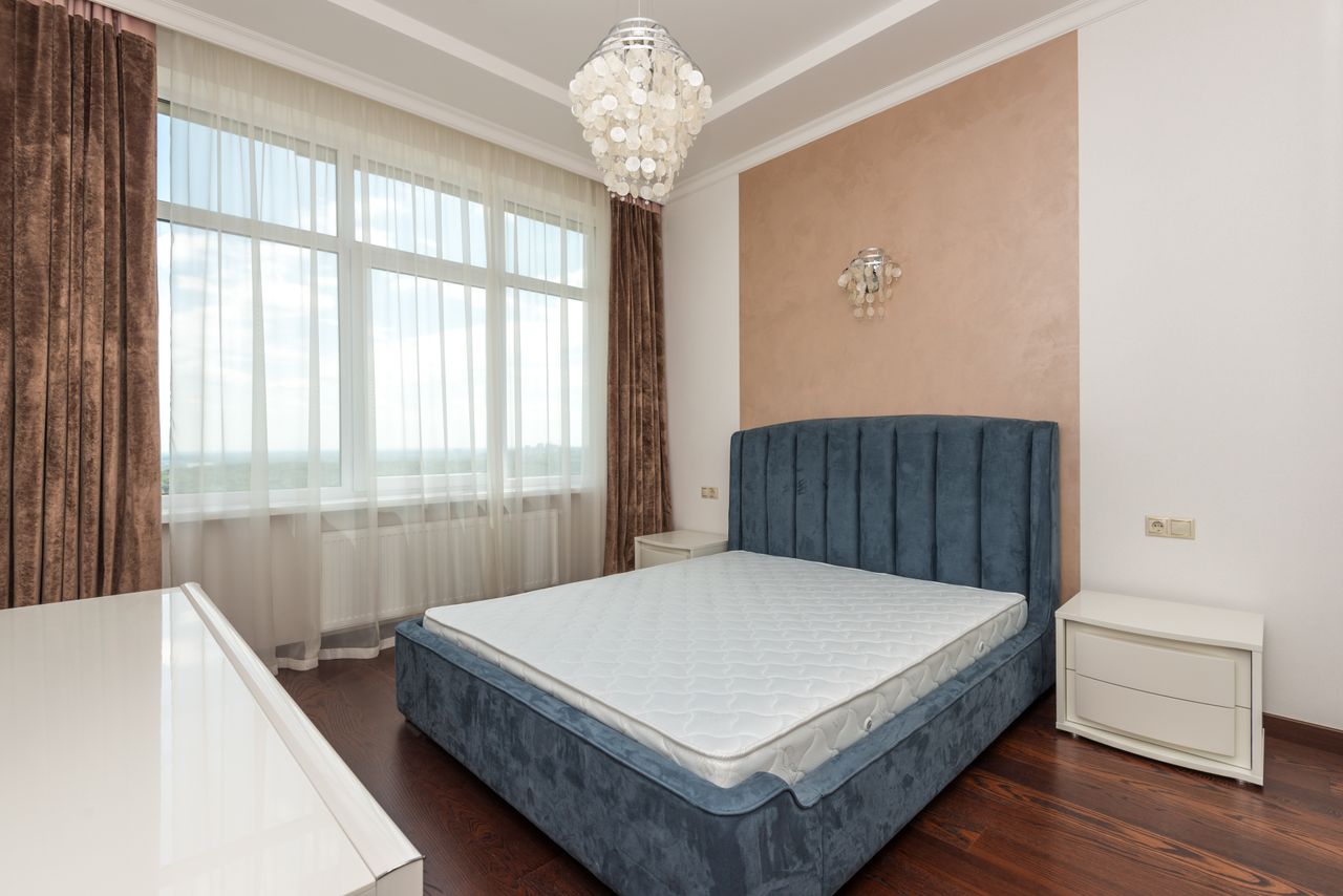 A cozy bedroom featuring a blue velvet bed, large windows, and chic decor.